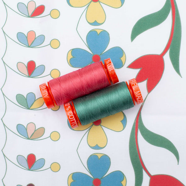 red and green spools of sewing cotton on printed fabric