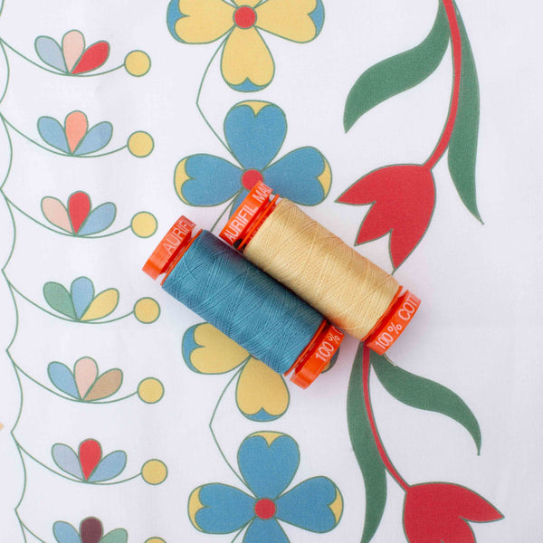 yellow and blue spools of Aurifil sewing cotton on printed fabric